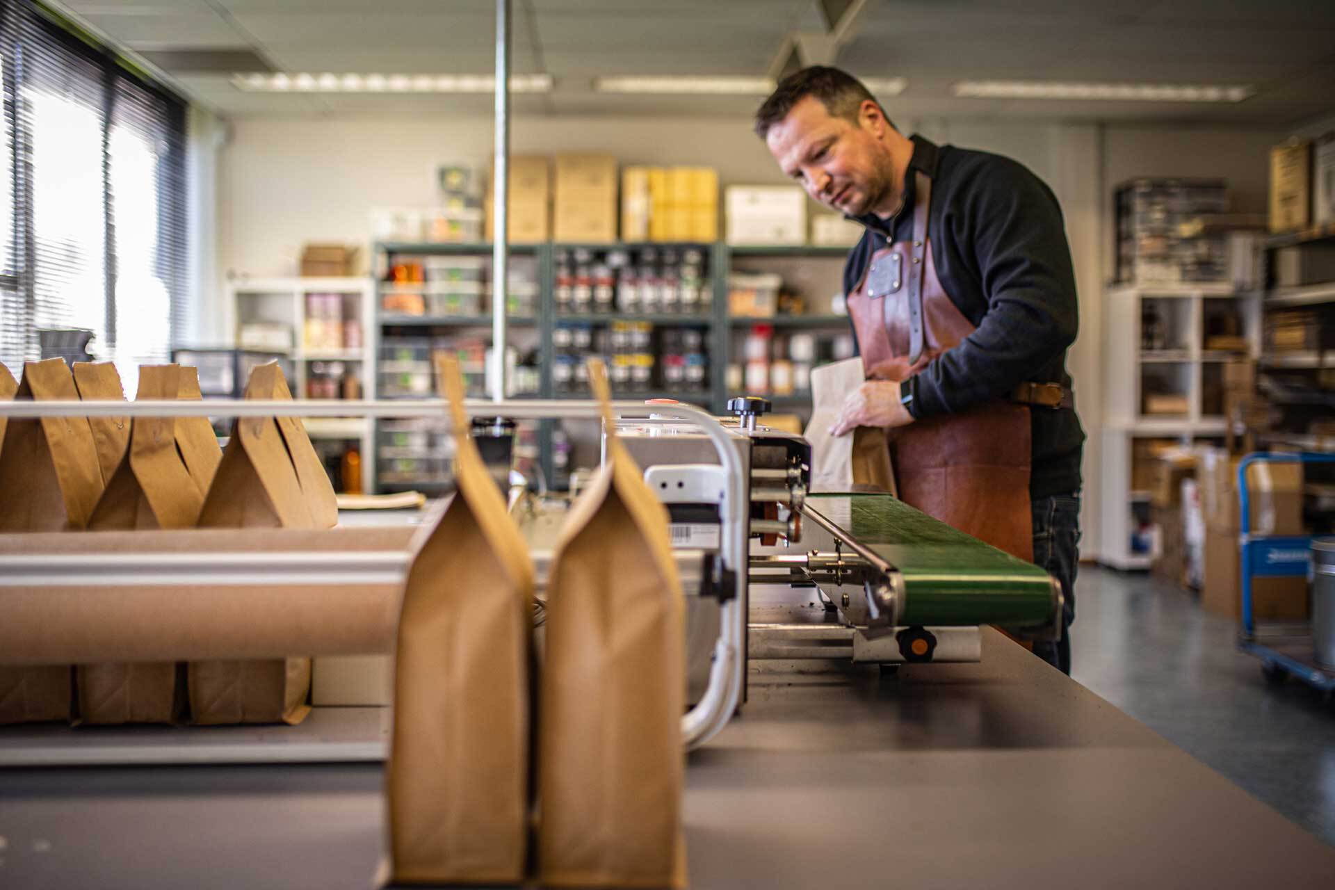 Erik Poelstra opent de koffiebrander machine en koffiebonen rollen eruit